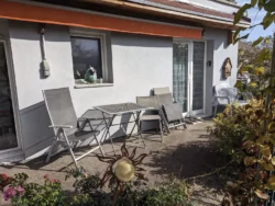 Table et chaises sur la terrasse fleurie du gîte Huth